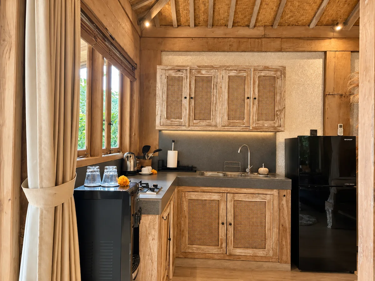 Small kitchen with timber cupboards, a dark countertop, sink and refrigerator beneath a thatched ceiling