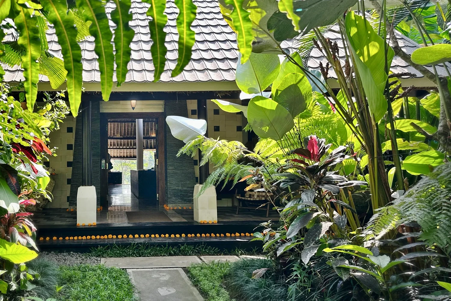 Warm wood and natural stone at the estate's entrance, framed by lush tropical foliage