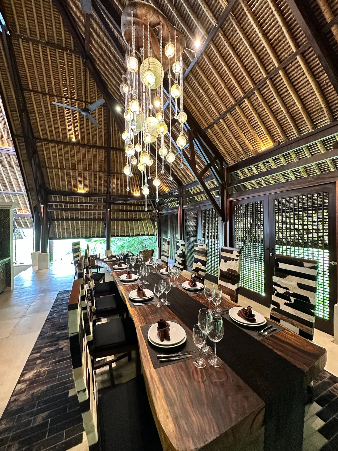A long table set for a private group beneath the estate's open-air thatched dining pavilion