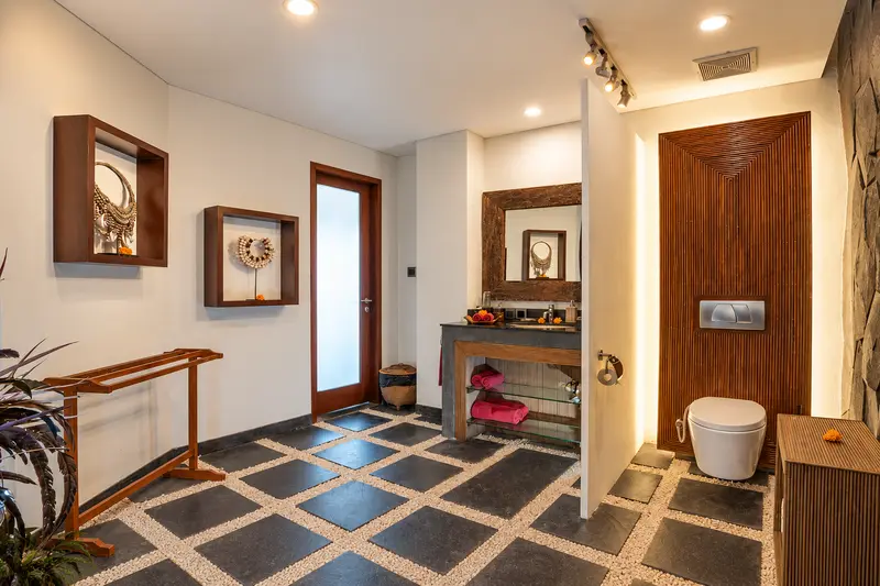 Golden Room bathroom showing a single washbasin, one toilet, timber fittings and a patterned stone floor