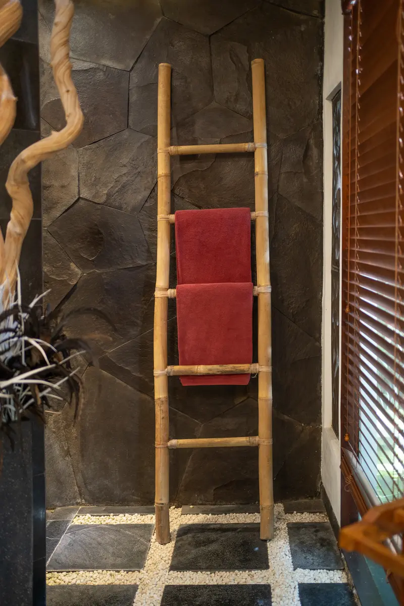 Timber towel ladder against a dark stone wall in the Golden Room bathroom