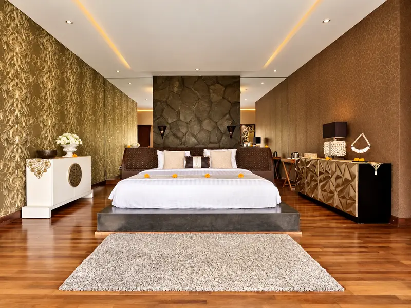 Golden Room bedroom with a large double bed, gold-patterned walls, a stone feature wall and polished timber flooring