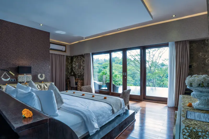 Reverse view of Golden Room showing the bed, timber floor and wide pool-facing glazed doors