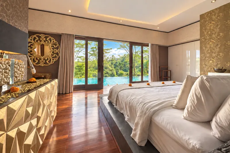 View from the Golden Room bed towards tall glazed doors, the swimming pool and tropical greenery