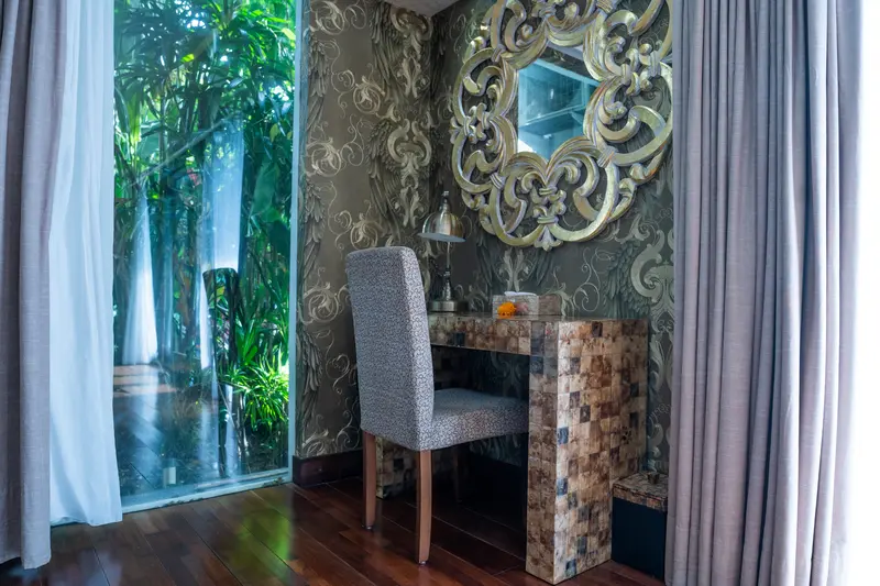 Writing desk and upholstered chair beside the Golden Room window and an ornate gold mirror