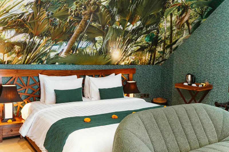 Front detail of the Green Room 1 double bed with botanical mural, green textiles and curved upholstered bench