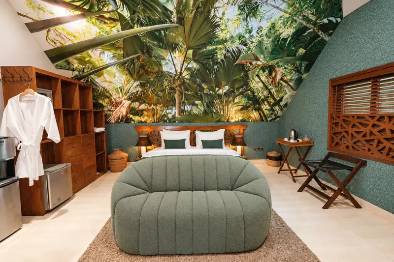 Green Room 1 bedroom with a large double bed, curved green bench, tropical wall mural and warm timber furniture