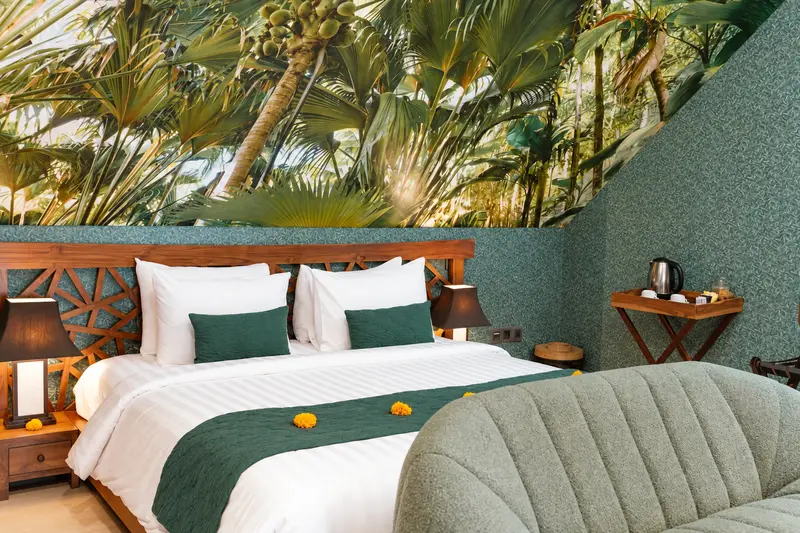 Side view of Green Room 1 showing the double bed, teal walls, tropical mural and curved upholstered bench