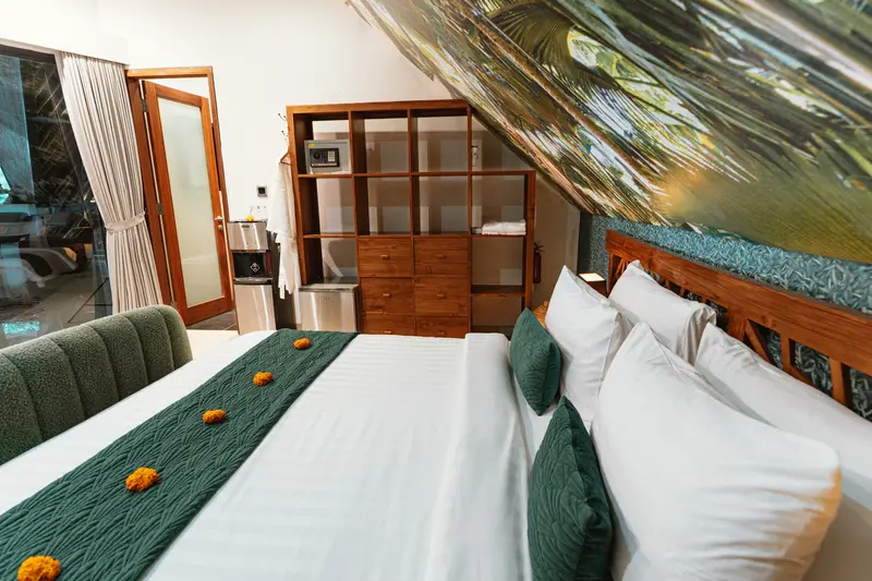 Green Room 1 bed beside open timber storage, in-room safe, water station and entrance door