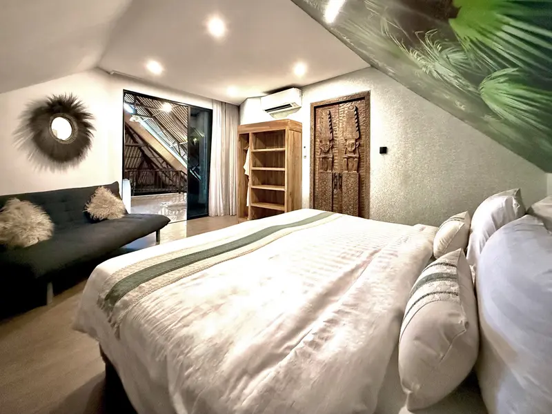 View from the Green Room 2 bed towards the sofa, timber storage, carved door and room entrance