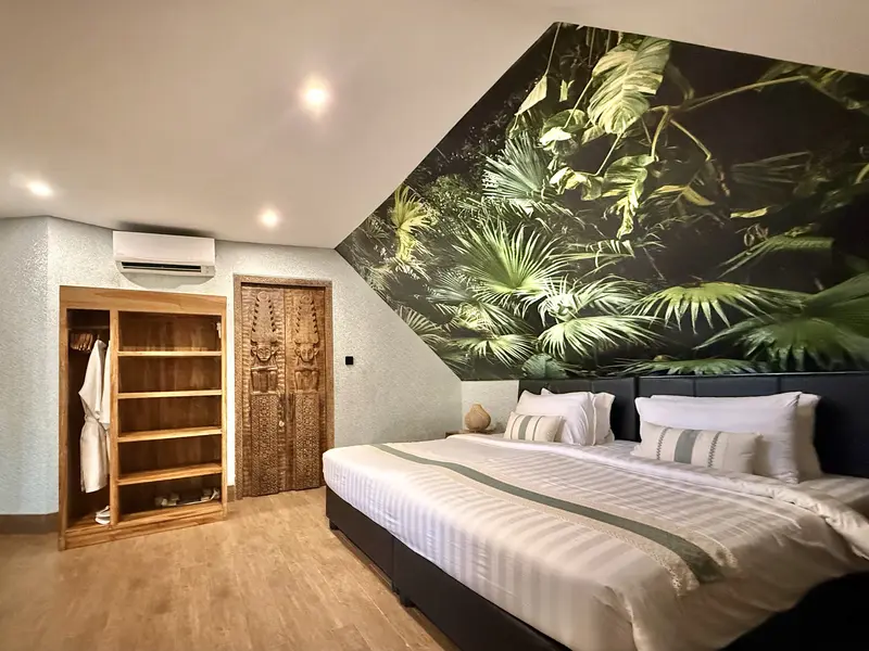 Green Room 2 double bed with tropical mural, open timber storage, carved timber door and air conditioning
