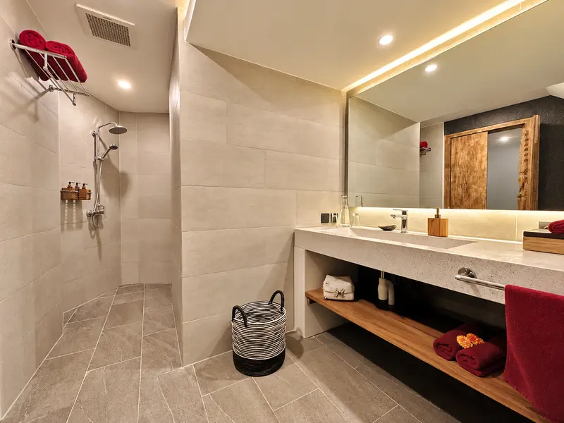 Green Room 2 bathroom showing an open walk-in shower, long washbasin counter and stone-look surfaces