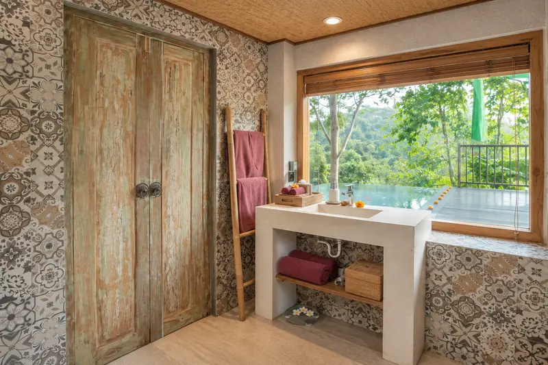 Joglo 1st Floor bathroom vanity beside a wide garden window and carved timber door