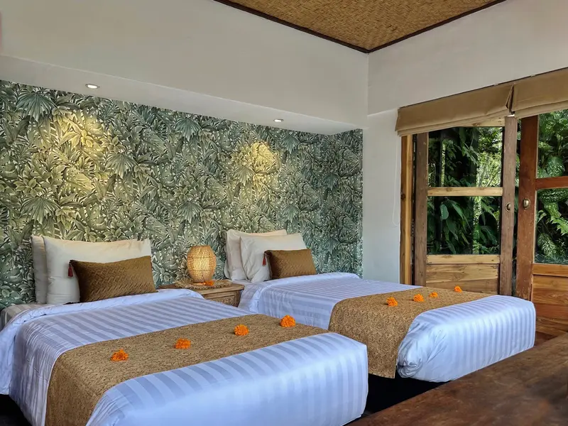 Closer view of the two single beds, woven runners and botanical wall in Joglo 1st Floor