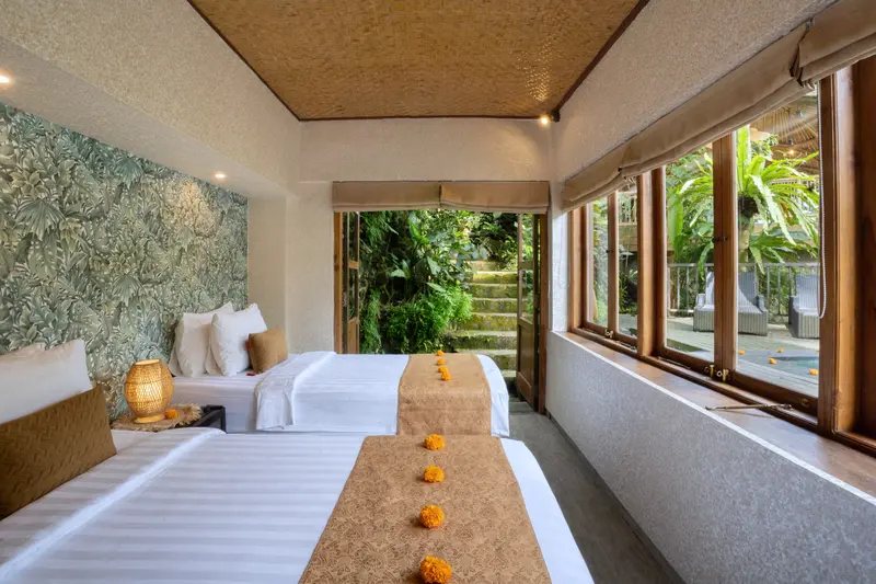 Joglo 1st Floor twin beds framed by corner windows looking onto tropical greenery and the pool