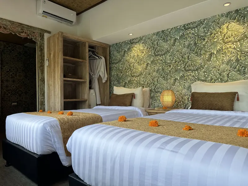 Side view across Joglo 1st Floor showing twin beds, an open wardrobe and air conditioning