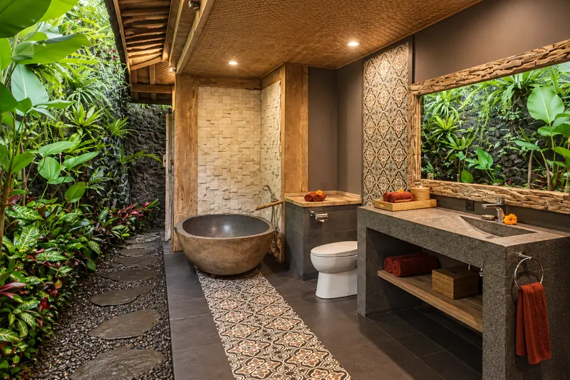 Main Joglo Room bathroom with a stone bathtub, one toilet, wide washbasin and open garden edge