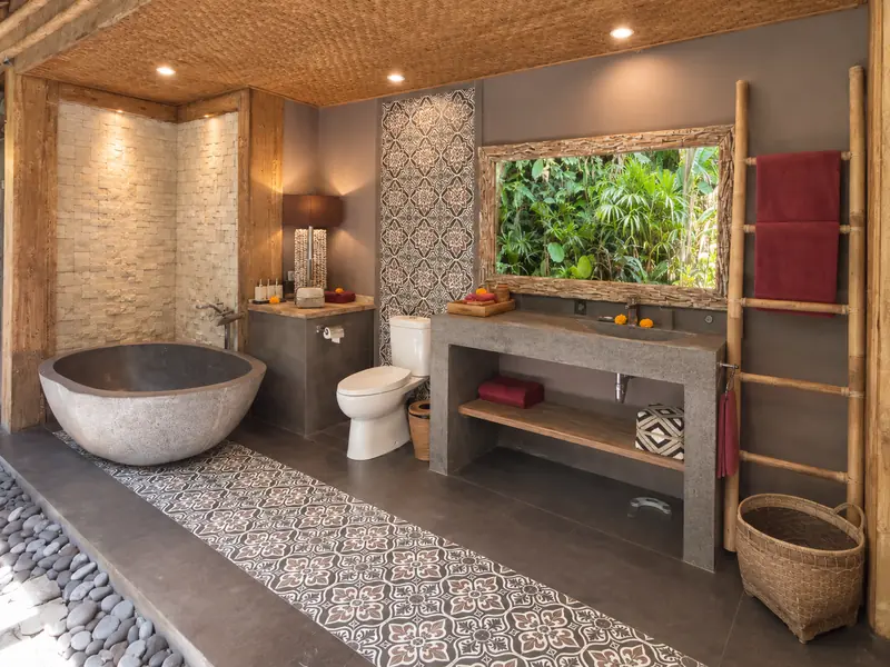 Open-air Main Joglo Room bathroom with freestanding stone bathtub, washbasin, toilet and tropical plants