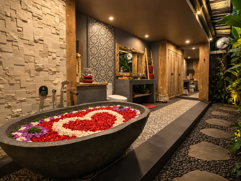 Main Joglo Room stone bathtub filled with a red, white, purple and green flower-petal arrangement