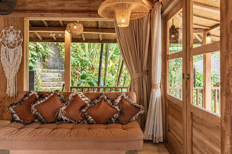 Main Joglo Room sofa beneath woven pendant lights beside wide timber windows and tropical greenery