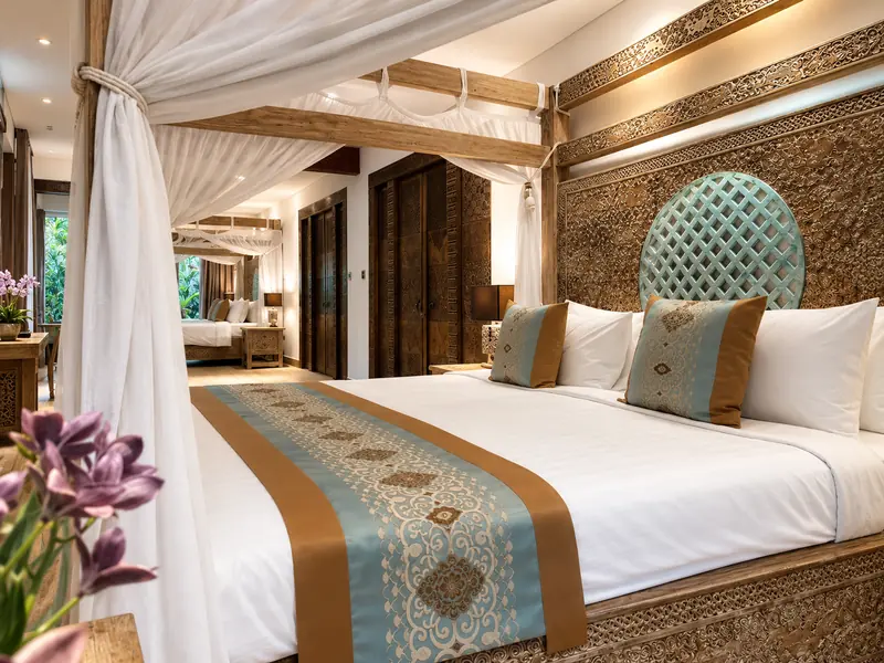 Close view of the Red Room double bed beneath white canopy drapes and an intricately carved timber frame
