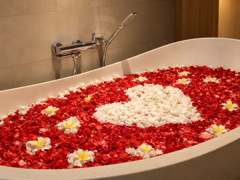 Close view of the Red Room freestanding bathtub decorated with red, white and yellow flower petals
