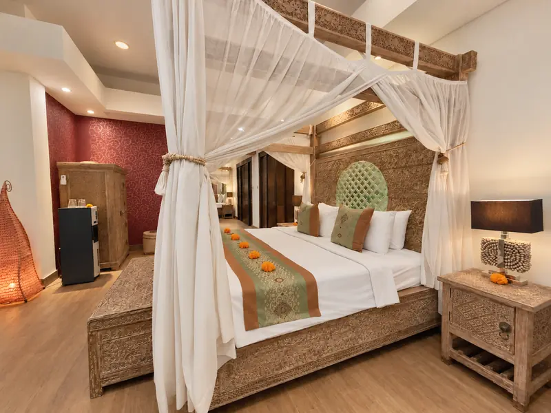 Side view of the Red Room canopy bed, carved bedside table and deep red feature wall