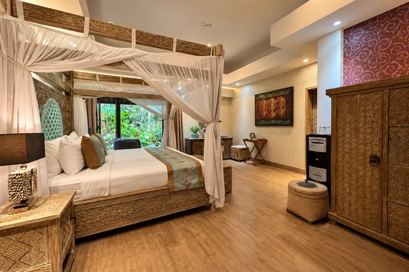 Angled view of Red Room with the canopy bed, carved wardrobe, ottoman, artwork and red feature wall