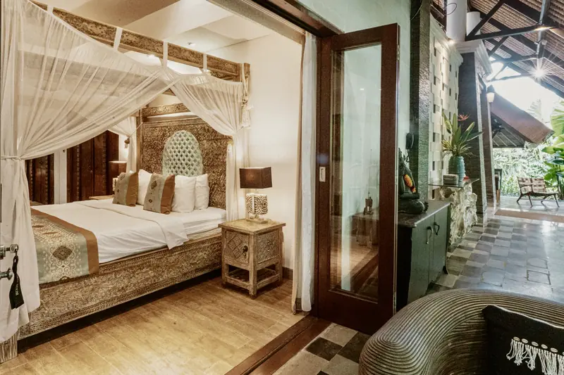 View from Red Room through an open glass door to a covered terrace surrounded by tropical greenery