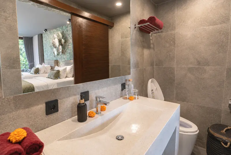 River Villa Room 1 bathroom area with long stone washbasin, wide mirror and one toilet