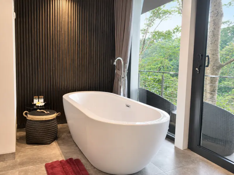 Closer view of the freestanding white bathtub and floor-mounted tap beside River Villa Room 1 balcony doors
