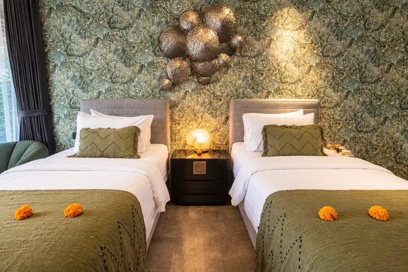 Front view of River Villa Room 1 with two single beds, botanical wall covering and sculptural wall art