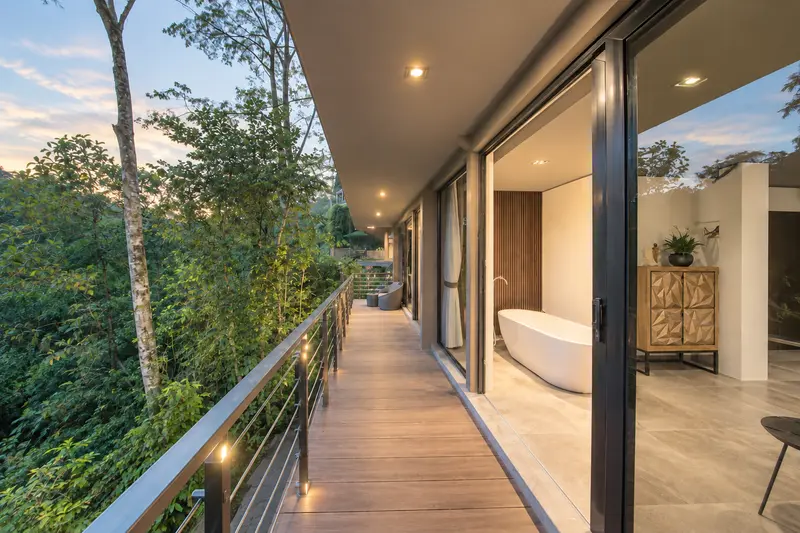 Long River Villa Room 2 balcony beside glass doors overlooking tropical trees at dusk