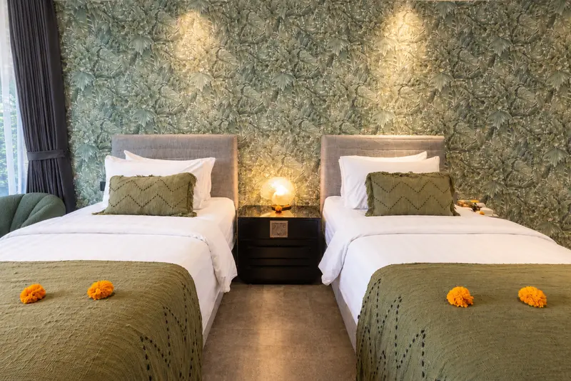 Front view of River Villa Room 3 with two single beds, olive runners and botanical wall covering