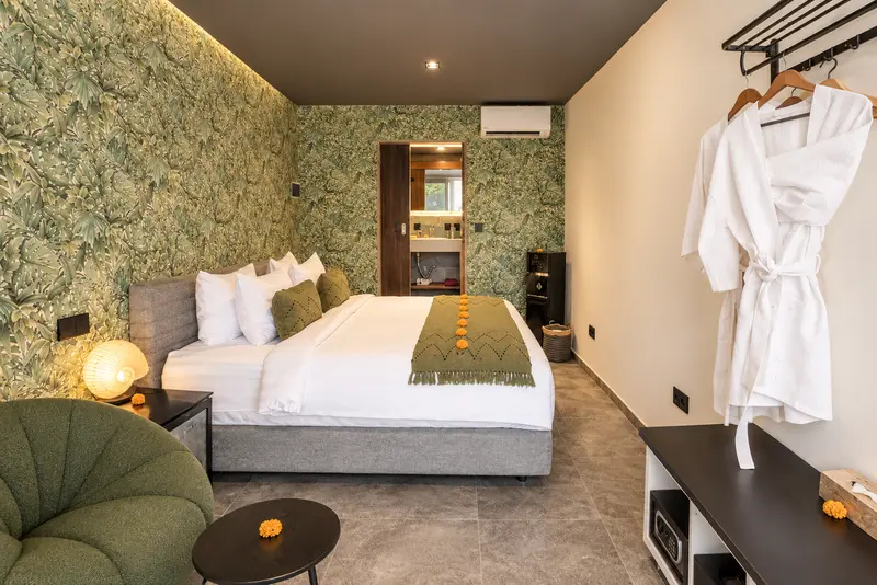 Reverse view of River Villa Room 4 with a joined large bed, lounge seating, hanging rail and bathroom entrance