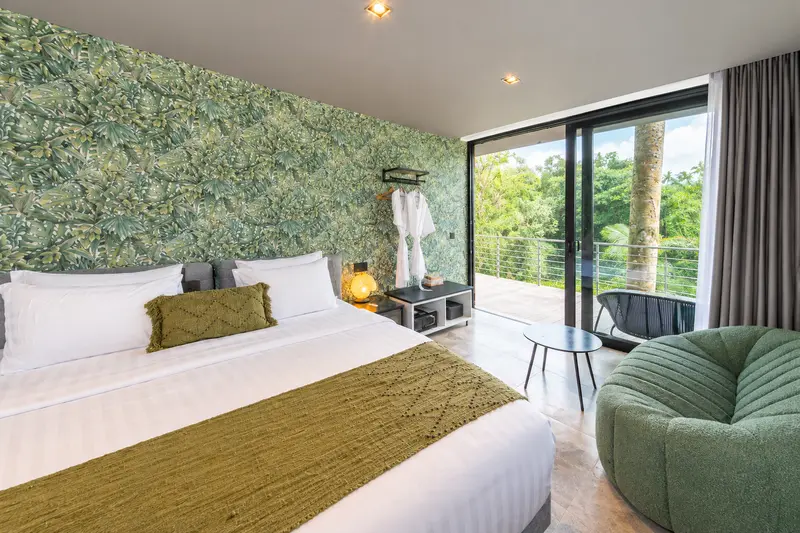 River Villa Room 4 with a joined large bed, botanical wall covering, lounge chair and open terrace