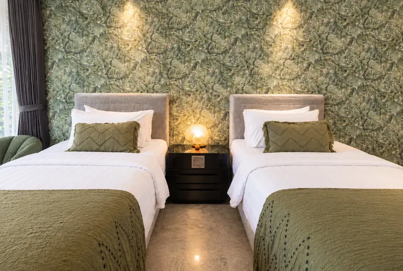 Front view of the two single beds in River Villa Room 5 with olive covers and warm bedside lighting