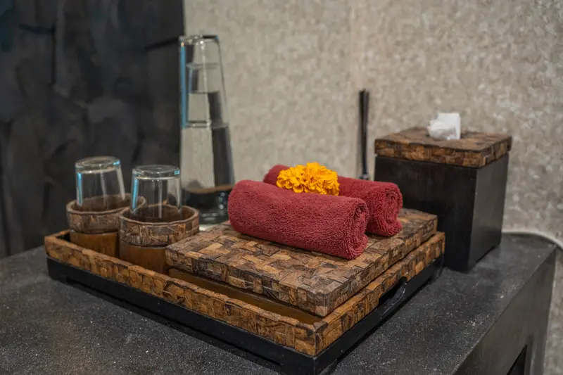 Studio Room 1 bathroom amenities arranged with rolled plum towels, water glasses and carved timber details