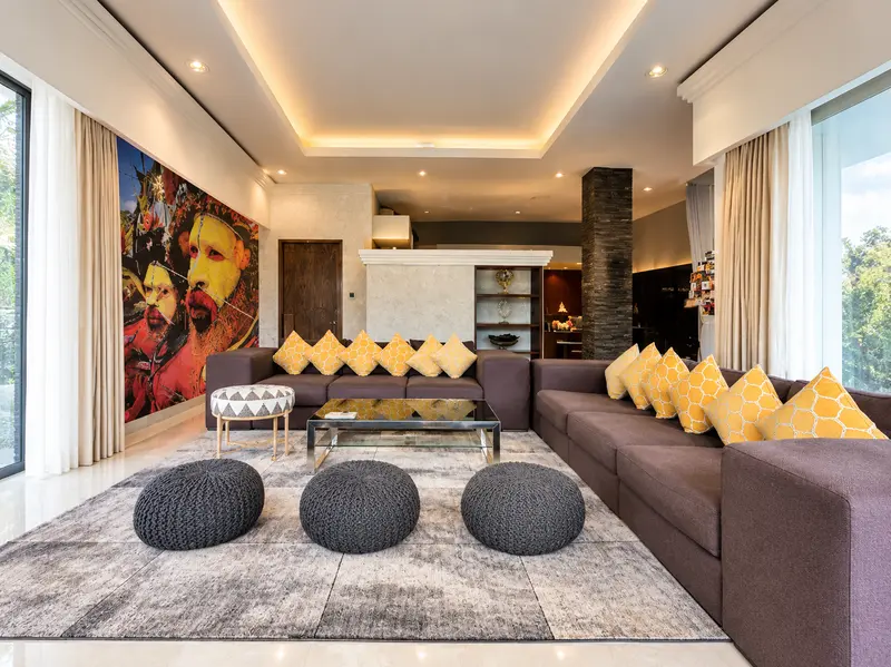 Studio Room 1 private lounge with large sectional seating, woven ottomans, vivid artwork and full-height garden glazing
