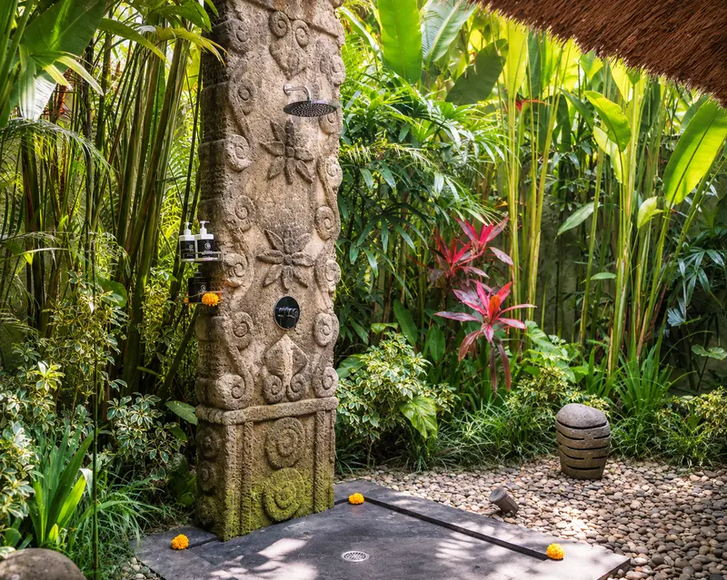 Studio Room 1 outdoor rain shower mounted on a carved stone column and surrounded by dense tropical plants