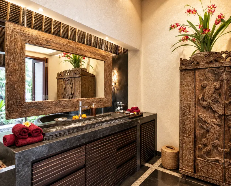 Studio Room 1 bathroom with a long dark-stone washbasin, timber-framed mirror and ornate carved cabinet