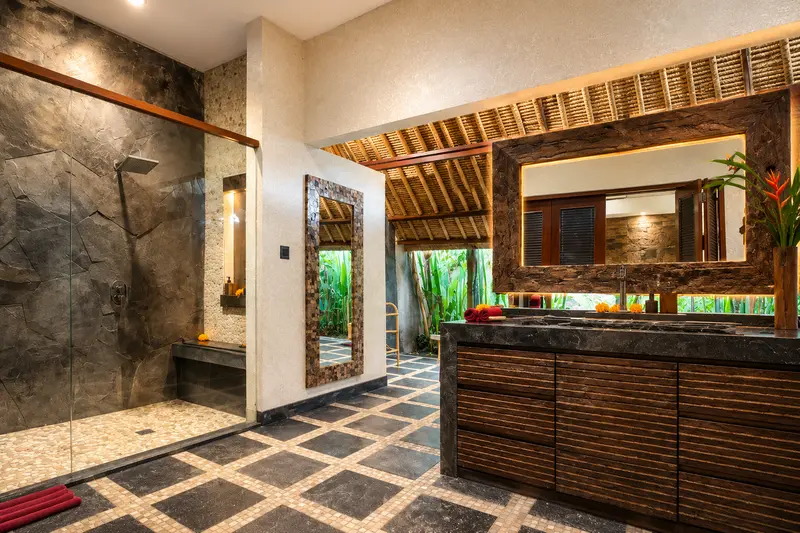 Wide bathroom view in Studio Room 2 with a long dark-stone washbasin, timber mirror and glass-enclosed rain shower
