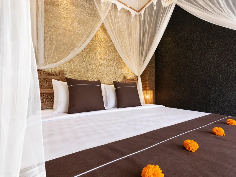 Front view of the Studio Room 2 large double bed with white canopy drapes, brown textiles and flower details